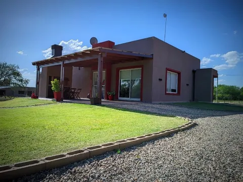 Fachada de la cabaña con galería y parque